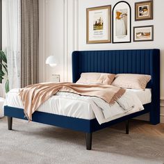 a bed with blue headboard and white sheets in a room next to a window