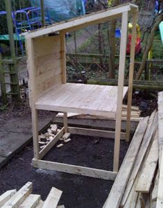 a wooden bench sitting in the middle of a yard next to piles of wood and logs