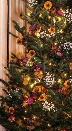 a decorated christmas tree in front of a door with lights and ornaments on the top