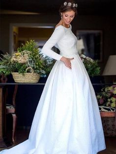 a woman in a white wedding dress standing next to a table with flowers on it