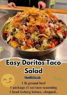 a bowl filled with taco salad sitting on top of a metal counter next to a sign