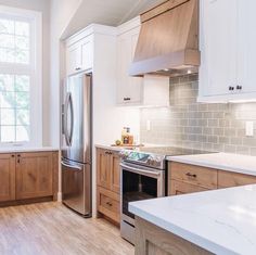 a kitchen with wooden cabinets and stainless steel refrigerator freezer combo in the center, along with white marble countertops