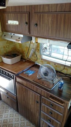 a stove top oven sitting inside of a kitchen next to wooden cabinets and counter tops