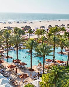 an aerial view of a beach resort with palm trees and people swimming in the pool