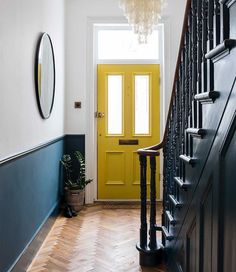 a bright yellow door is next to a wooden staircase