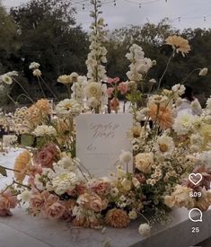 a table topped with lots of flowers and a sign