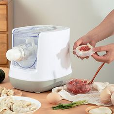 a person is preparing food in front of an electric juicer on a table with other ingredients