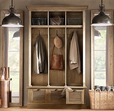 a wooden bench sitting under a window next to a coat rack with coats hanging on it