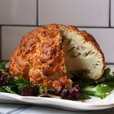 there is a cauliflower that has been cut in half on a plate with lettuce