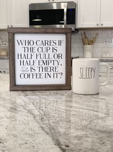 a coffee mug sitting on top of a kitchen counter next to a sign that says who cares if the cup is half full or half empty