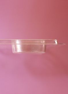 an empty plastic container hanging on a pink wall