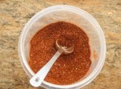 a blender filled with red stuff on top of a counter next to a wooden spoon