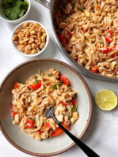 a bowl filled with noodles and vegetables next to bowls of other food on the table