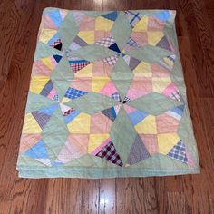 a multicolored patchwork quilt on the floor with wood floors in the background