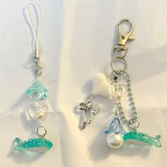 two keychains with charms attached to them on a white tablecloth covered surface