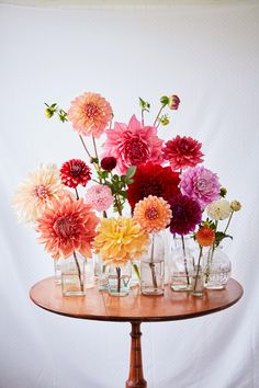 a wooden table topped with lots of vases filled with flowers on top of it