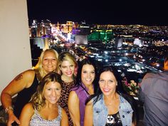 a group of women standing next to each other in front of a city at night