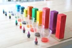 several cups are lined up on a table with colored pencils in them and one is empty