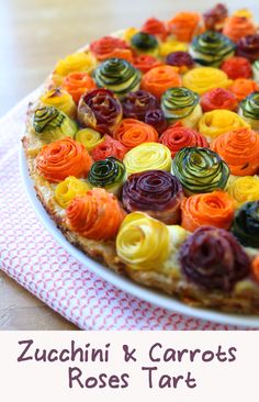 a colorful pizza on a plate with the words zucchini & carrots rose tart