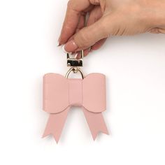 a hand holding a pink bow shaped key chain