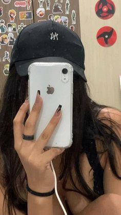 a woman is taking a selfie with her cell phone and hat over her head