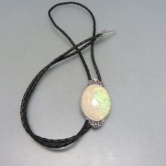 This lovely handmade bolo tie features a gorgeous oval acrylic stone of opal or opaline set into a vintage Victorian style silvertone metal bezel. The bolo slide is nicely sized at 2 3/8ths inches tall and 1 1/4 inches wide at the middle. It is new, never worn and placed on a 36 inch long Braided black leatherette string tie with silvertone metal end caps. The stone radiates green, pink and orange coloring. This will arrive in a lovely gift box. If you like old bolo ties, vintage western accesso Kalispell Mt, Bolo Ties, Bolo Tie, Long Braids, Vintage Victorian, Vintage Western, Victorian Style, Victorian Fashion, Lovely Gift