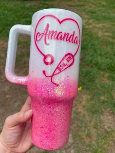 a hand holding a pink and white cup with the words amanda on it in red ink