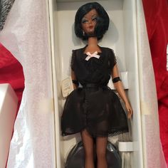 a doll in a white box with black clothes