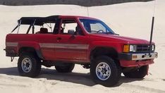 a red pick up truck parked in the sand