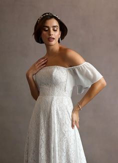 a woman in a white wedding dress with her hands on her chest and wearing a tiara