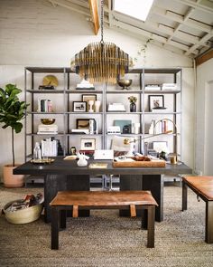 a room with a table, shelves and two benches in front of the desk is filled with books