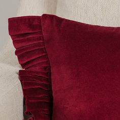 a red pillow with ruffled edges on a white couch