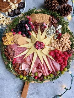 a platter filled with meats, cheeses and nuts next to pine cones