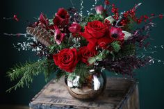 a vase filled with red roses and greenery