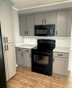 an empty kitchen with black appliances and white cabinets