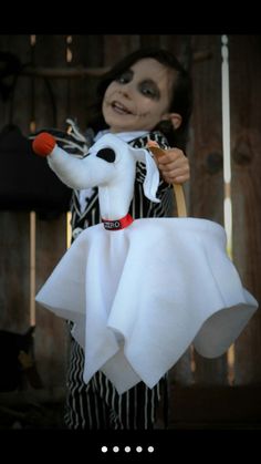 a young boy dressed up as a ghost holding a stuffed animal