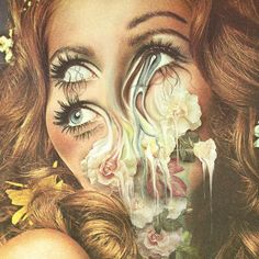 a woman's face with long eyelashes and flowers in her hair is surrounded by petals