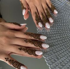 two hands with henna tattoos on their fingers and one hand holding a white manicure