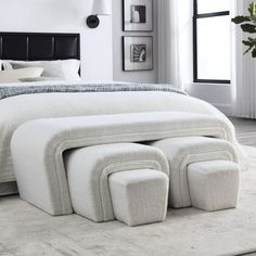 a white bed with four foot stools in front of it