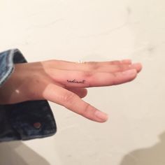 a person's hand with a small tattoo on the middle finger that says, i love you