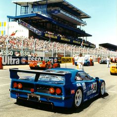 the race cars are racing down the track in front of an empty stadium full of people