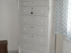 a white dresser sitting next to a window with polka dot curtains on the windowsill