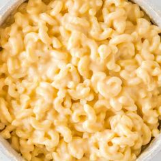 macaroni and cheese is in a bowl on a white surface, ready to be eaten