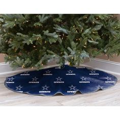 a christmas tree skirt with the word cowboys on it in front of a christmas tree