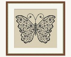 the cross stitch butterfly is shown in a brown frame and it's wings are spread out