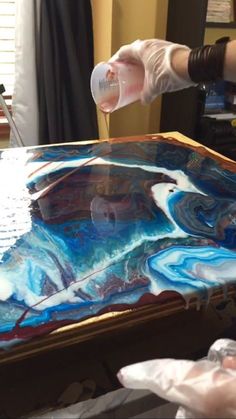 a person is pouring liquid into a large piece of art on top of a table