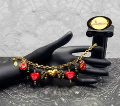 Inspired by the Gothic and Victorian era,  Gloriana has designed this Fabulous Gothic yet Elegant and Romantic, hearts and cameo charm bracelet for a very different look.  It is sure to become one of your favorites and will truly give your outfits a beautiful touch of style!!  MADE WITH : - Black colored, gold plated, oval shaped acrylic cameo beads with Swarovski Crystal accents and stainless steel backings. - Red colored, gold plated, oval shaped acrylic cameo beads with Swarovski Crystal acce Handmade Metal Charm Bracelet For Valentine's Day, Gothic Gold Bracelets For Gifts, Gold Gothic Bracelets For Gifts, Gold Gothic Bracelet For Gift, Handmade Vintage Bracelets For Valentine's Day, Heart-shaped Vintage Charm Bracelets For Gifts, Heart-shaped Vintage Charm Bracelets As Gift, Heart-shaped Vintage Charm Bracelet For Gifts, Victorian Goth Jewelry