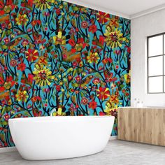 a bath tub sitting next to a wall covered in colorful floral designs on it's side