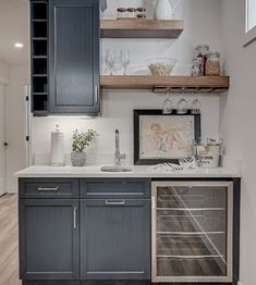 a kitchen with gray cabinets and white counter tops, an open wine cooler in the corner