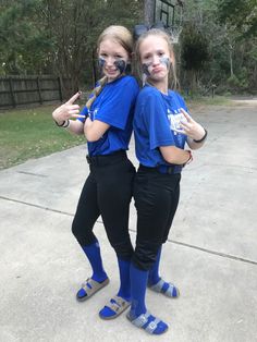 two girls in blue shirts and black pants posing for the camera with their arms around each other